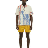 Man wearing a white shirt with a graphic design, yellow shorts, and a bucket hat on a white background