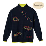 Navy knit sweater with neon yellow and red embroidered fish names, including 'Striped Bass', 'Atlantic Cod', 'Sardines', and 'Great White Shark (Human)'. Features ribbed cuffs and hem with yellow contrast detail, and red embroidered 'Tombolo' text at the waist.