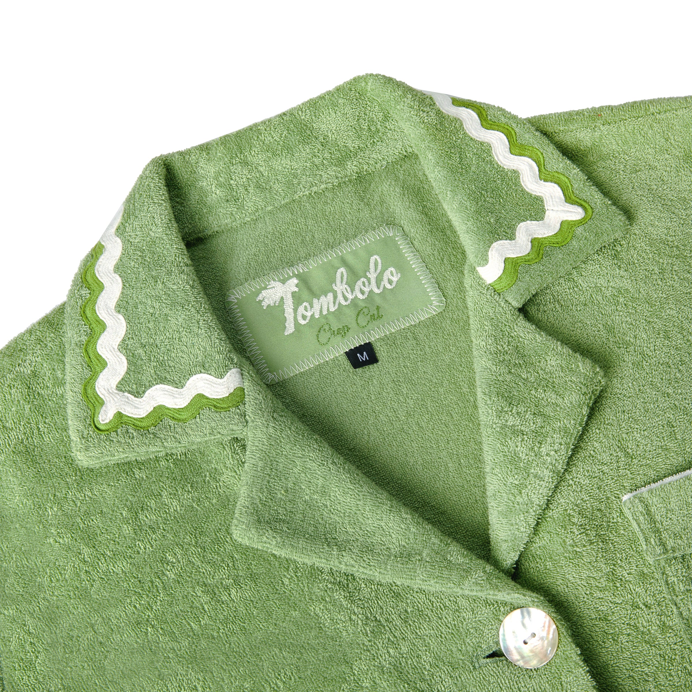 Close-up product image of the 'Rick Rack' Cabana ~ Crop Cut's (Green) custom interior woven label and oversized agoya shell buttons.