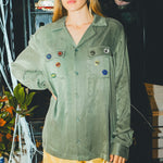 Woman wearing a green SNL shirt and sunglasses in front of a bar cabinet. 