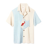 Short-sleeved button-up terry cloth shirt with a split design: light blue on the left and beige on the right. A red hermit crab appliqué decorates the chest on a blue and white shell.