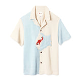 Short-sleeved button-up terry cloth shirt with a split design: light blue on the left and beige on the right. A red hermit crab appliqué decorates the chest on a blue and white shell.