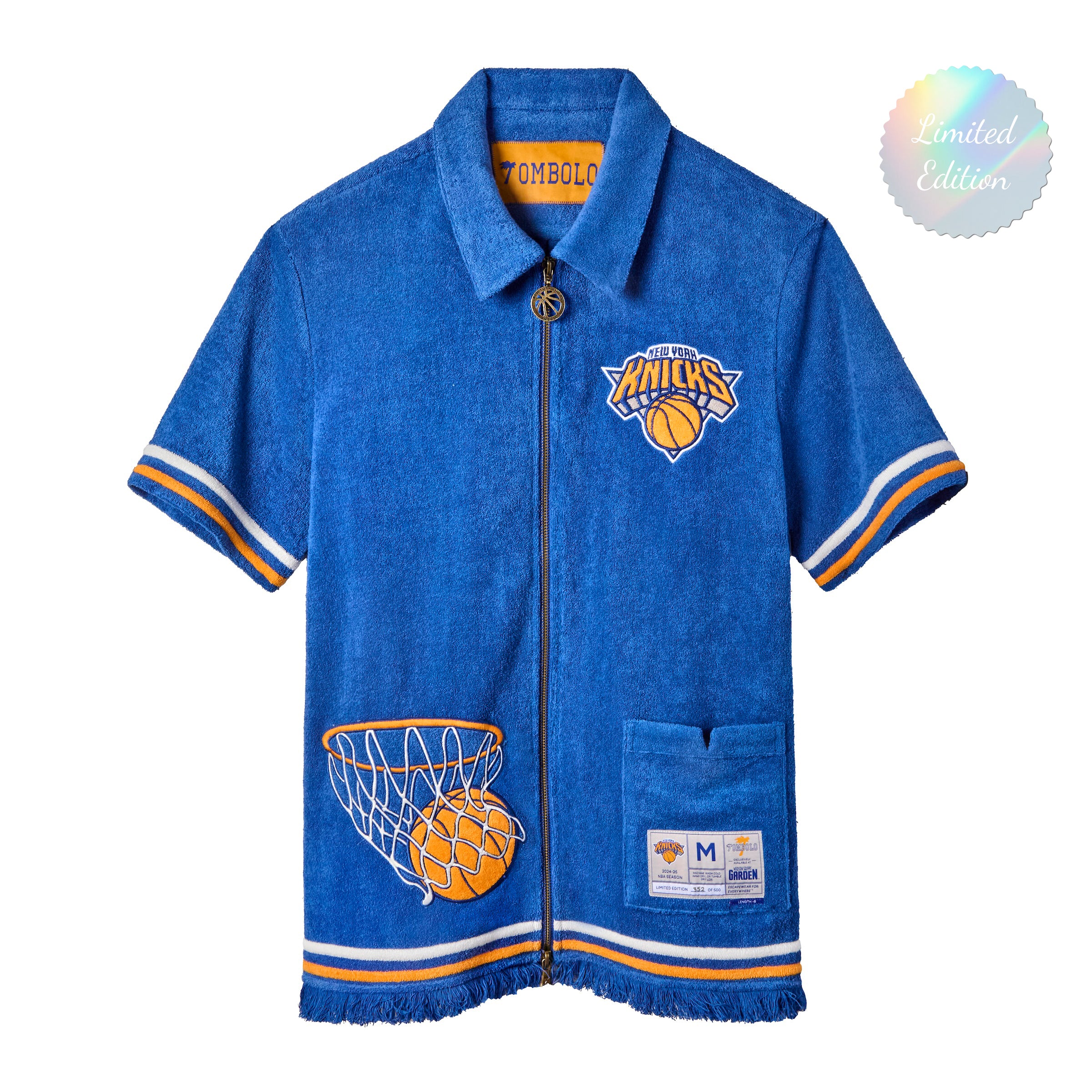 A bright blue terry cloth short-sleeve zip-up shirt with New York Knicks basketball details, including the Knicks logo, a basketball hoop patch on the lower side, and white-and-orange striped trim.