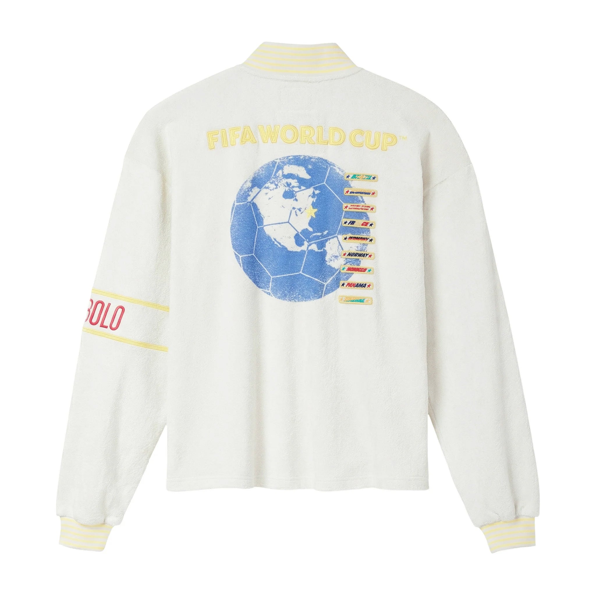 Back view of cream long-sleeve quarter-zip shirt with yellow “FIFA World Cup” lettering and large blue globe graphic with team list on the back, plus striped yellow ribbed collar and cuffs.
