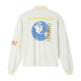 Back view of cream long-sleeve quarter-zip shirt with yellow “FIFA World Cup” lettering and large blue globe graphic with team list on the back, plus striped yellow ribbed collar and cuffs.