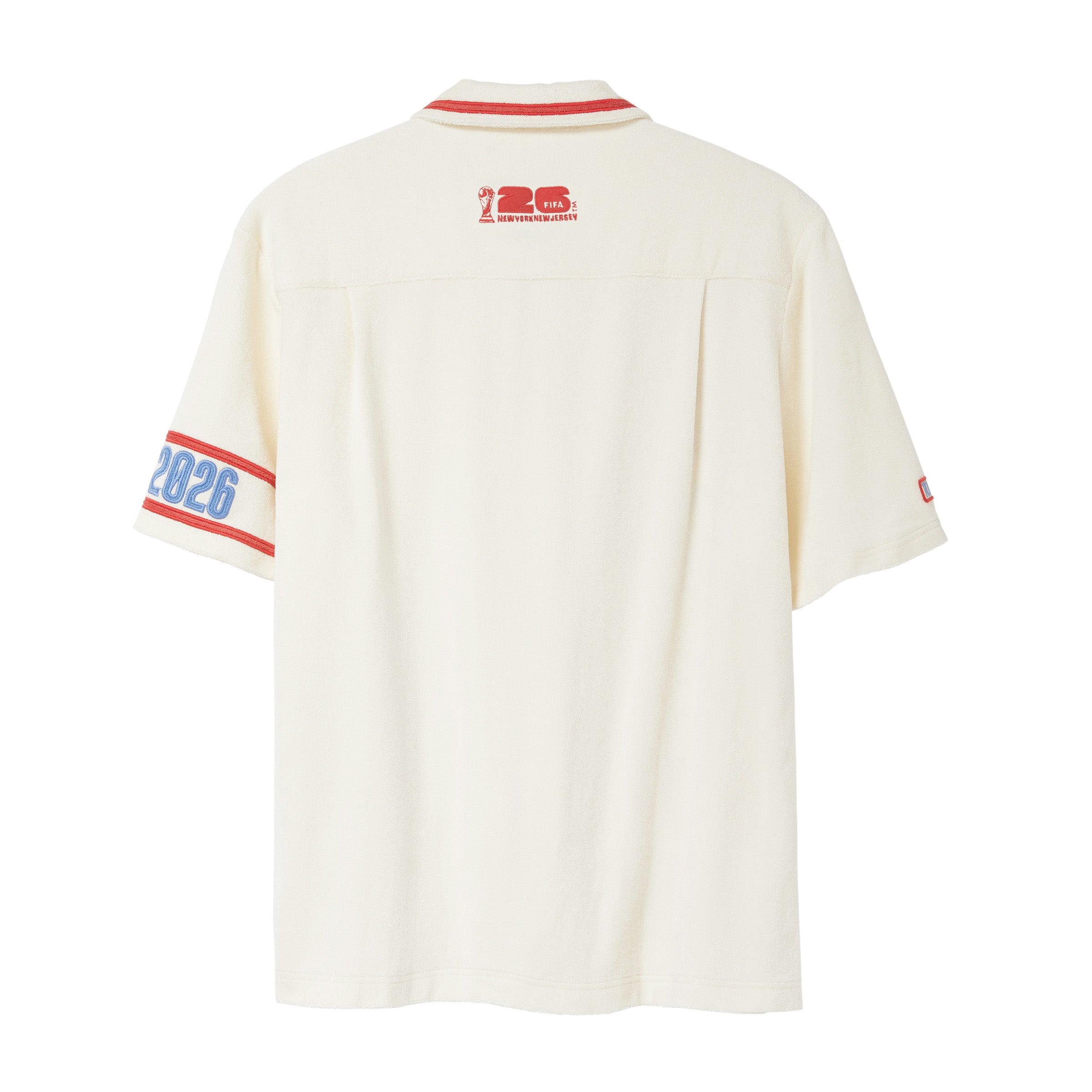 Back of beige short-sleeve cabana shirt with red collar piping, FIFA World Cup 26 logo below collar, and 2026 armband detail on wearer’s left sleeve.