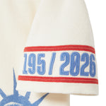 Close-up of beige cabana shirt sleeve with red trim and embroidered 1951 / 2026 armband.