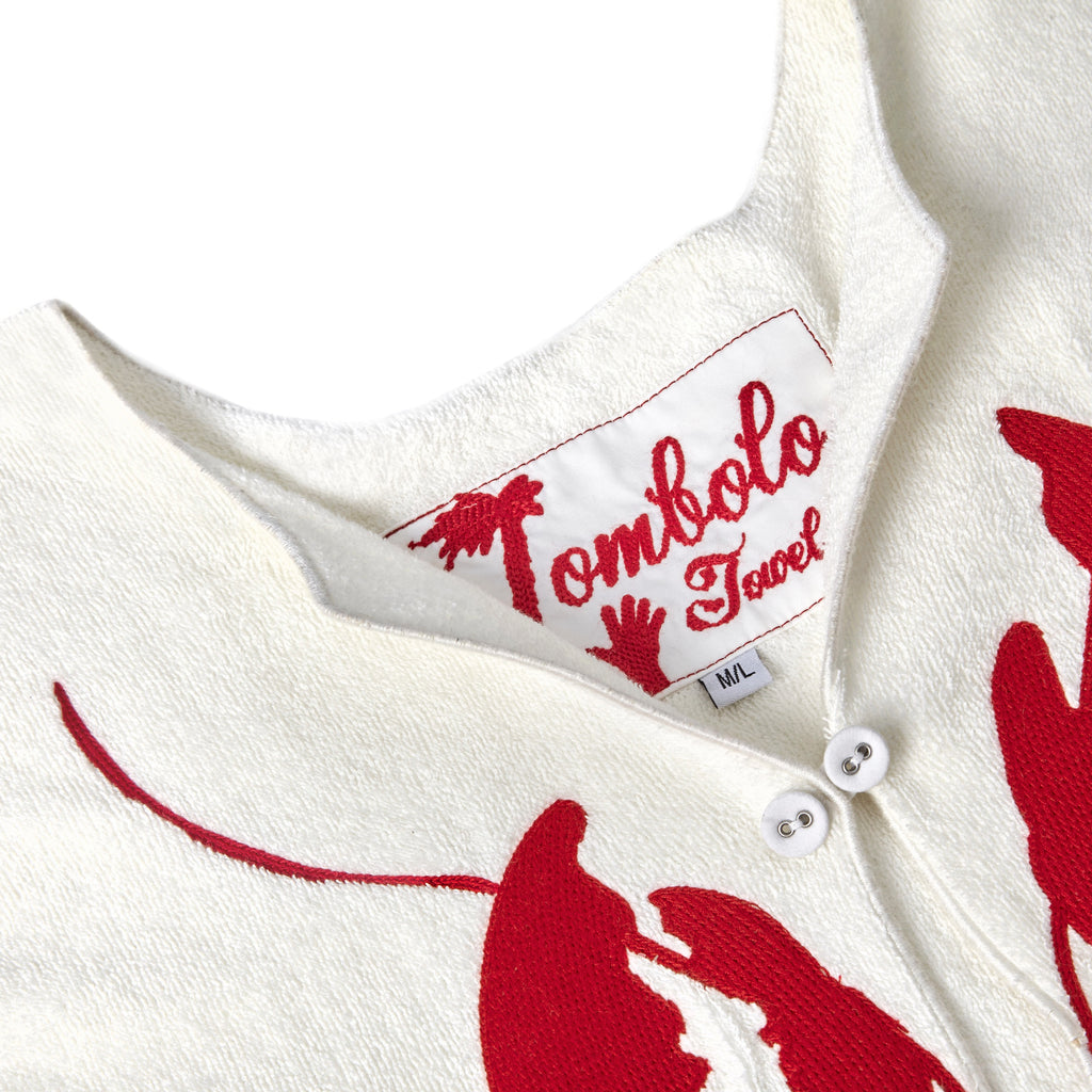 Close-up image of the 'Better Half' Hand Towel Top's chain-stitched interior label with a hand motif, and top button.