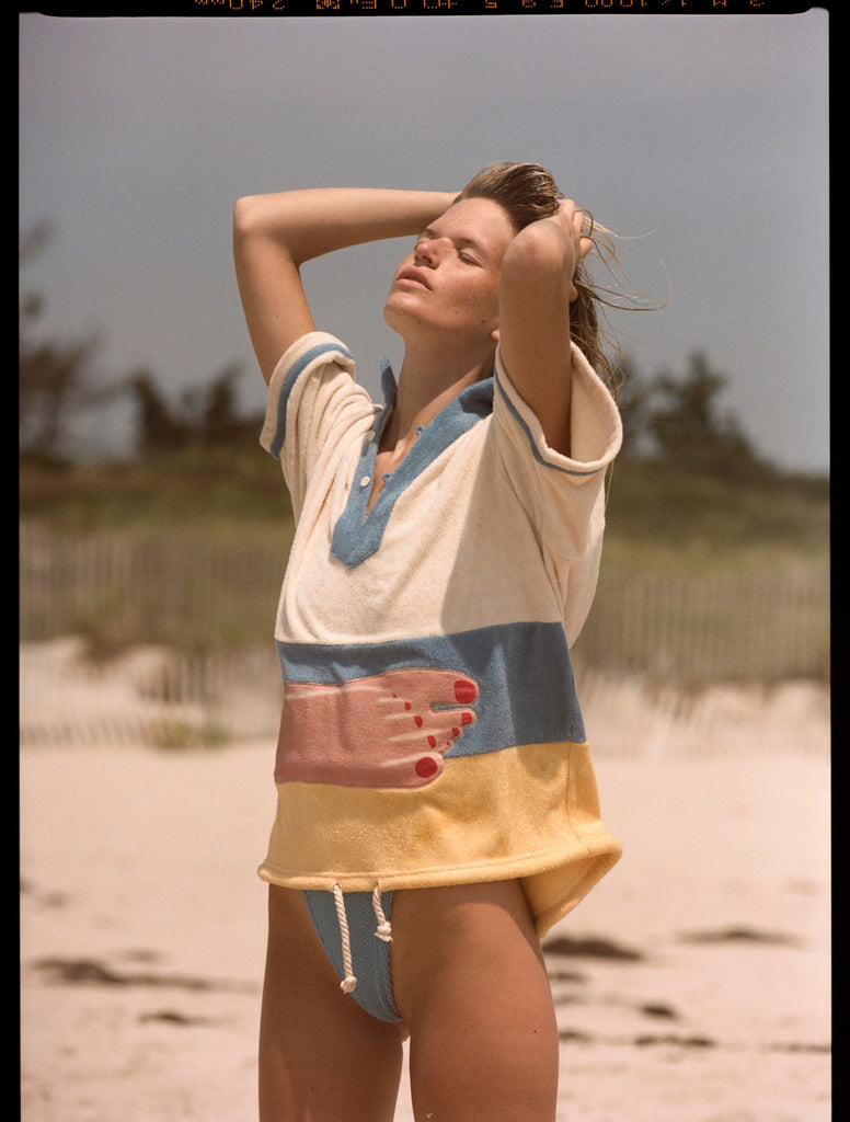 Woman puts hands through her hair and closes her eyes while looking up to the sky