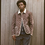 Man wears brown jacket and striped pants