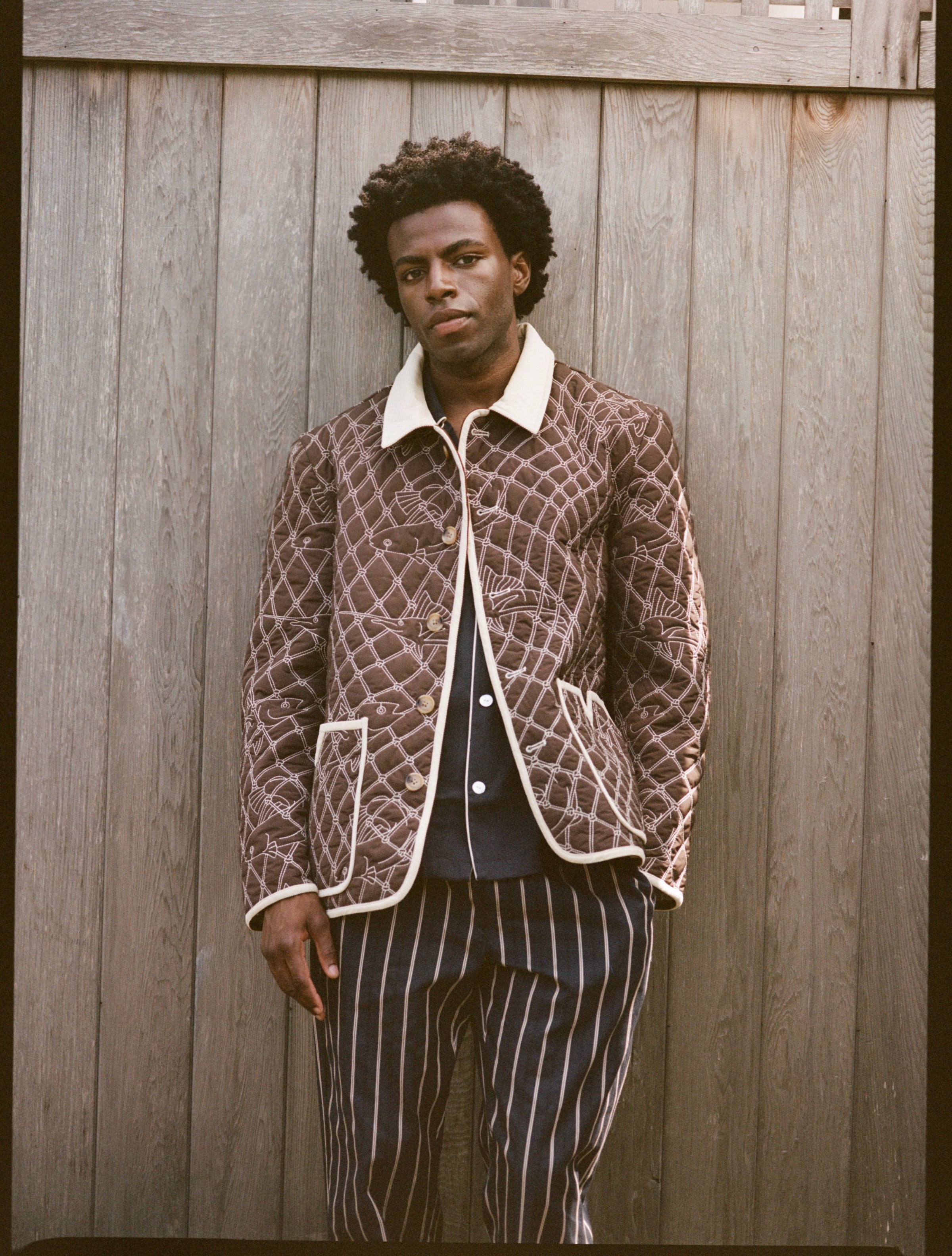 Man wears brown jacket and striped pants