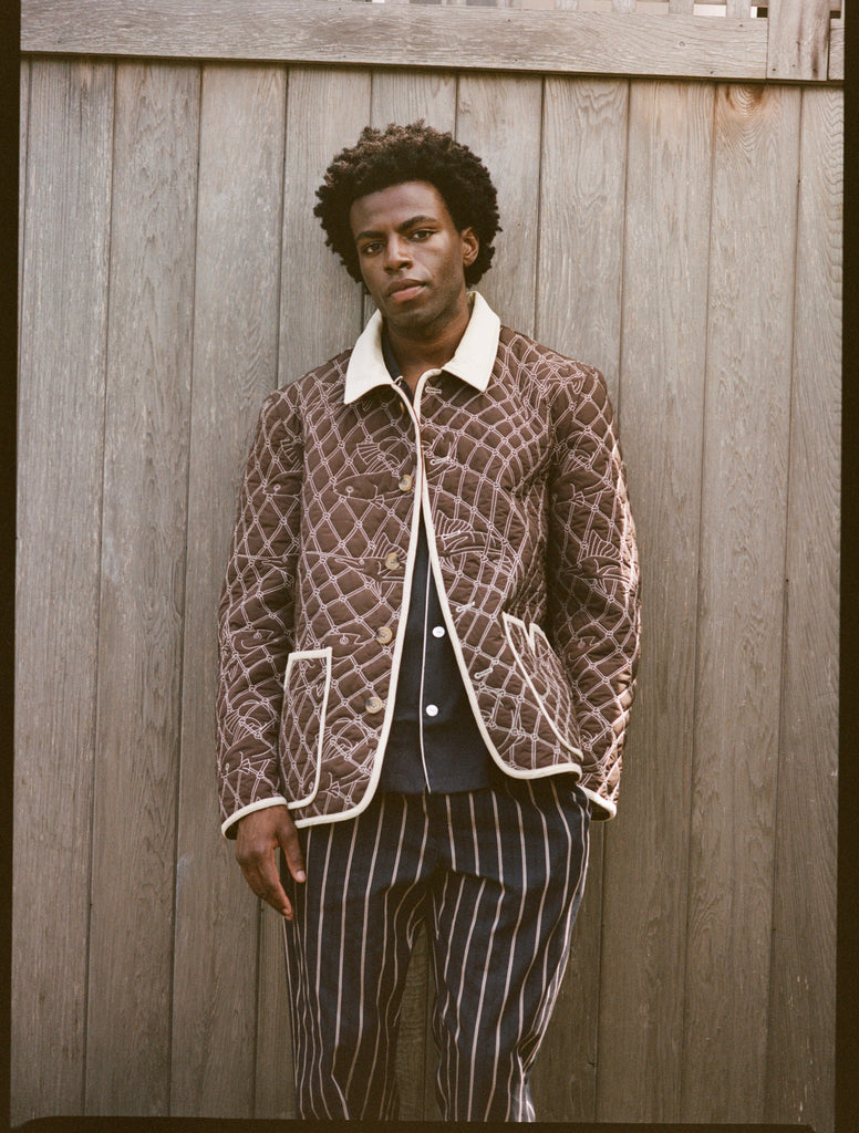 Man wears brown jacket and striped pants