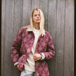 Woman holds jacket with her left hand 