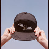two hands hold the souvenir cap to the sky 