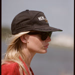 Side on portrait of woman wearing cap and sunglasses gazing into the distance