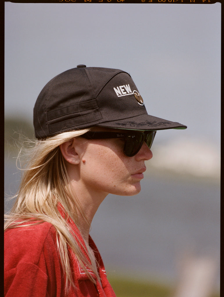 Side on portrait of woman wearing cap and sunglasses gazing into the distance