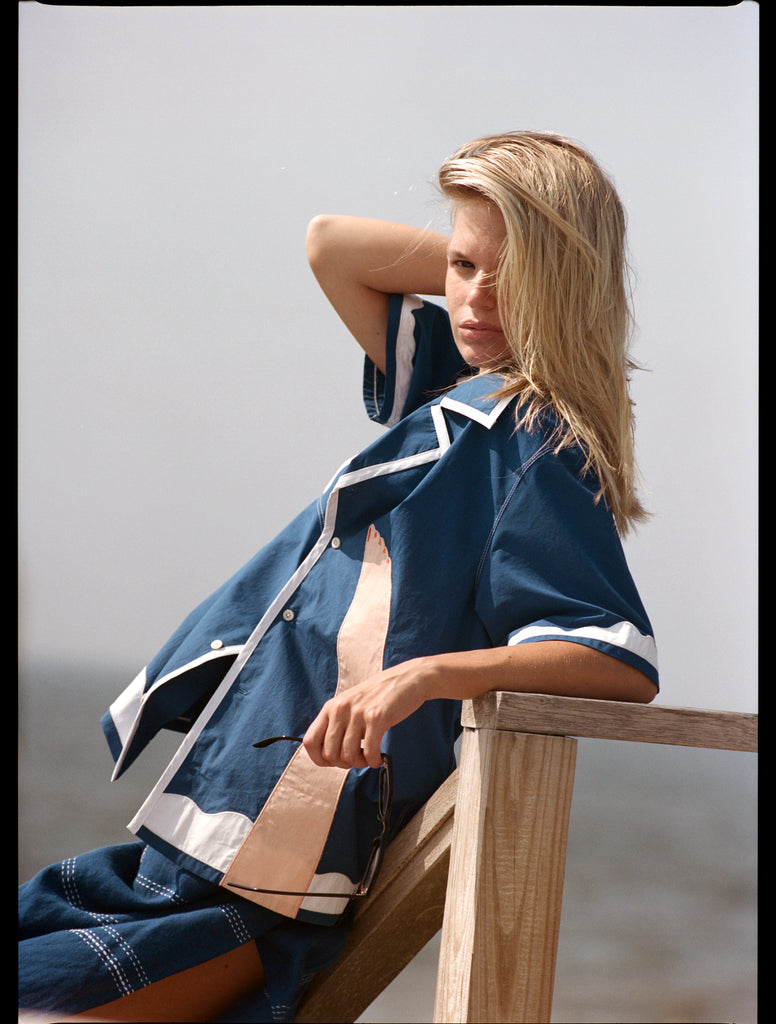 Woman leans against bannister with one arm behind her head
