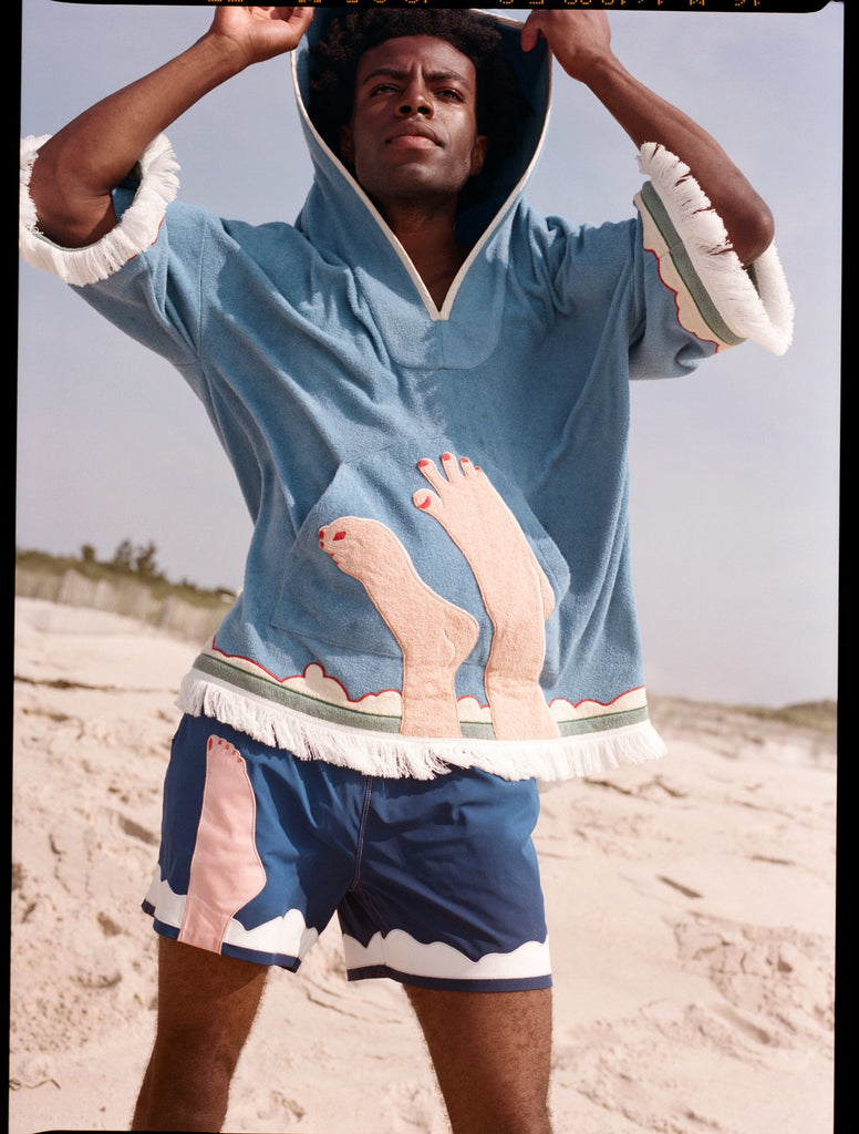 man looks above camera holding hood over head