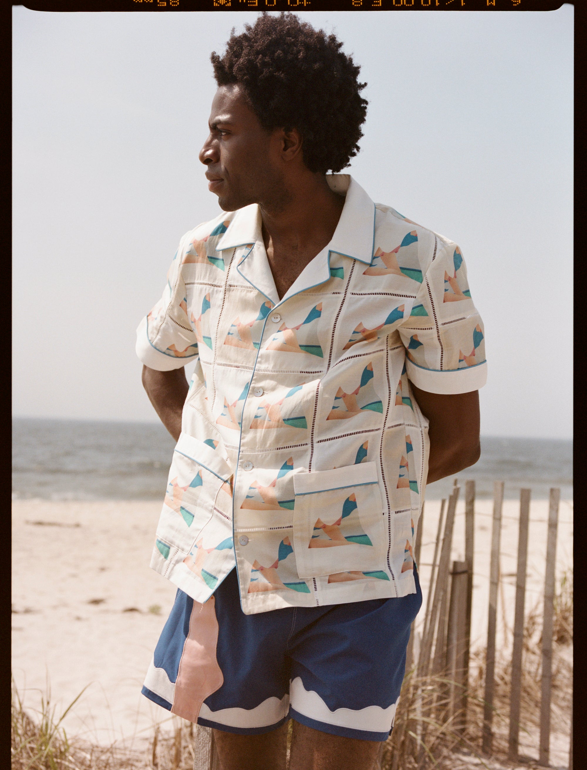 Man places hands behind back and looks off into the distance