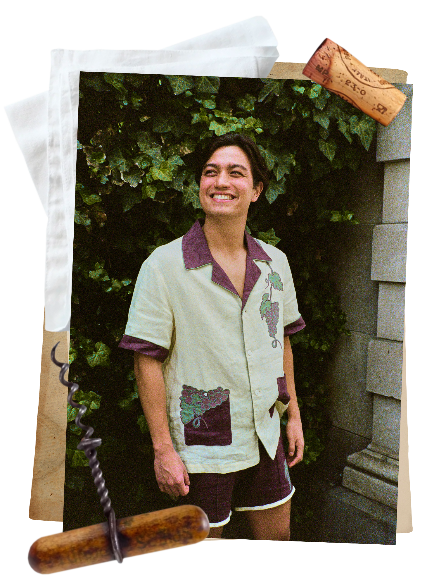 Man smiles in front of an ivy wall wearing a full wine-themed linen Tombolo set 