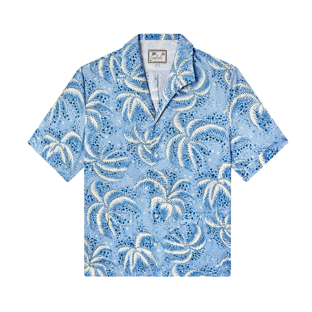Front-facing product image of 'Palm Fronds (Blue)' that features a vintage print of repeating palm fronds, a curved camp collar with no notch that lays flat, and V-slits on cuffs and lower patch pockets, shot on a white background.