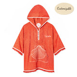Orange terrycloth poncho with white trim, featuring a large embroidered seashell design on the front pocket and the word 'Tombolo' stitched in white. 