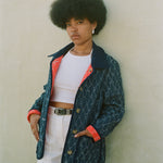 Woman leans against wall in unbuttoned jacket