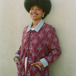 Woman leans against wall with hands in jacket pockets