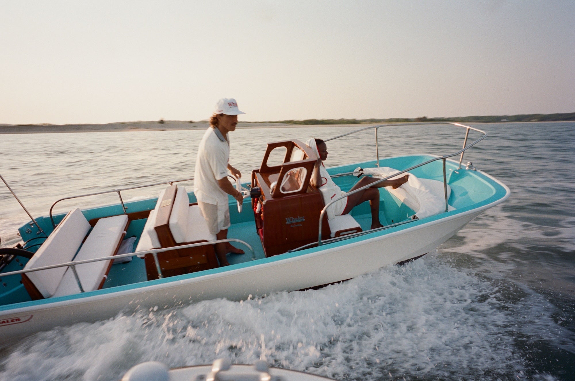 Two people on a boat in the water with a clear sky.