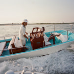 Two people on a boat in the water with a clear sky.