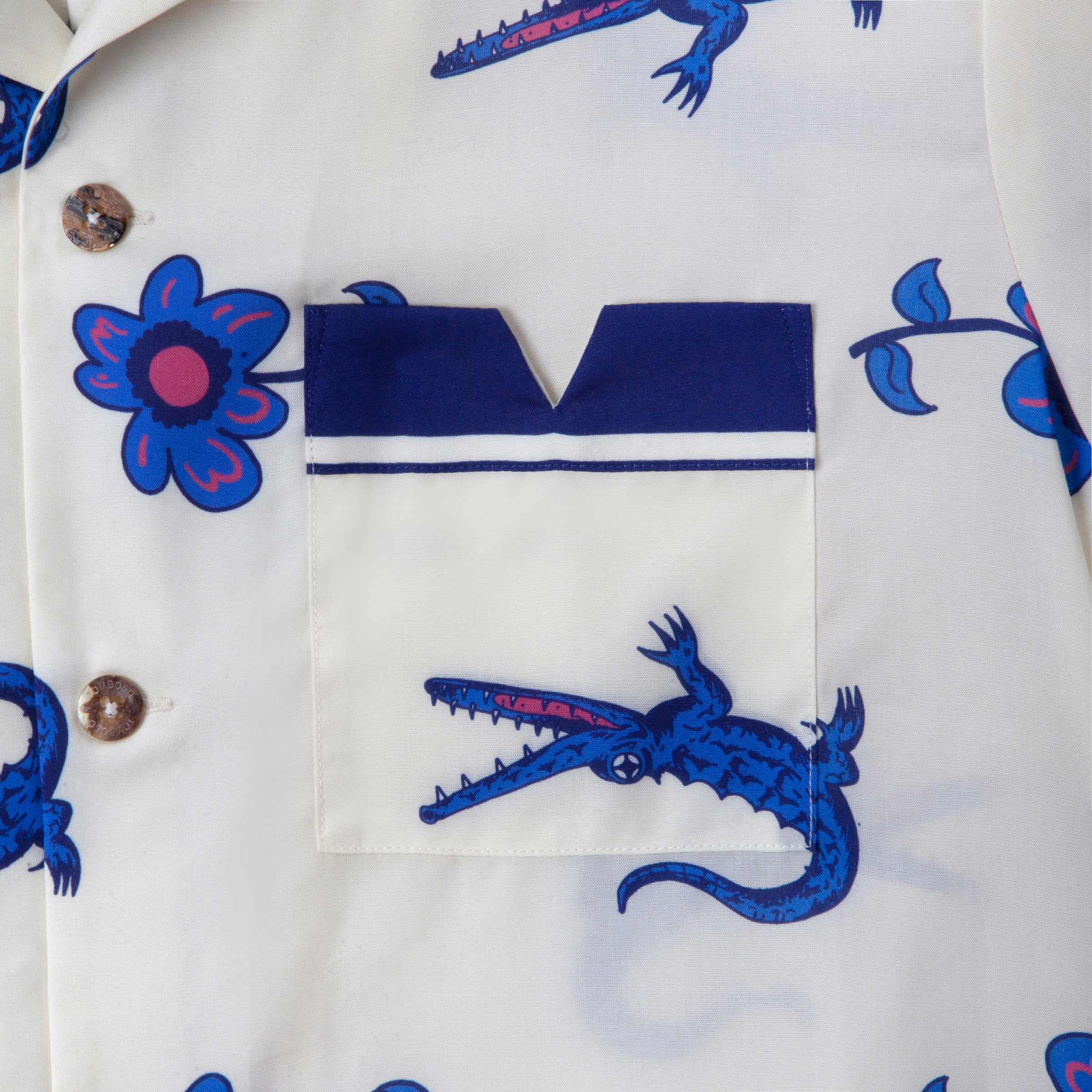 Close up detail of front left pocket featuring digitally printed artwork of purple crocodiles and flowers in repeat. 