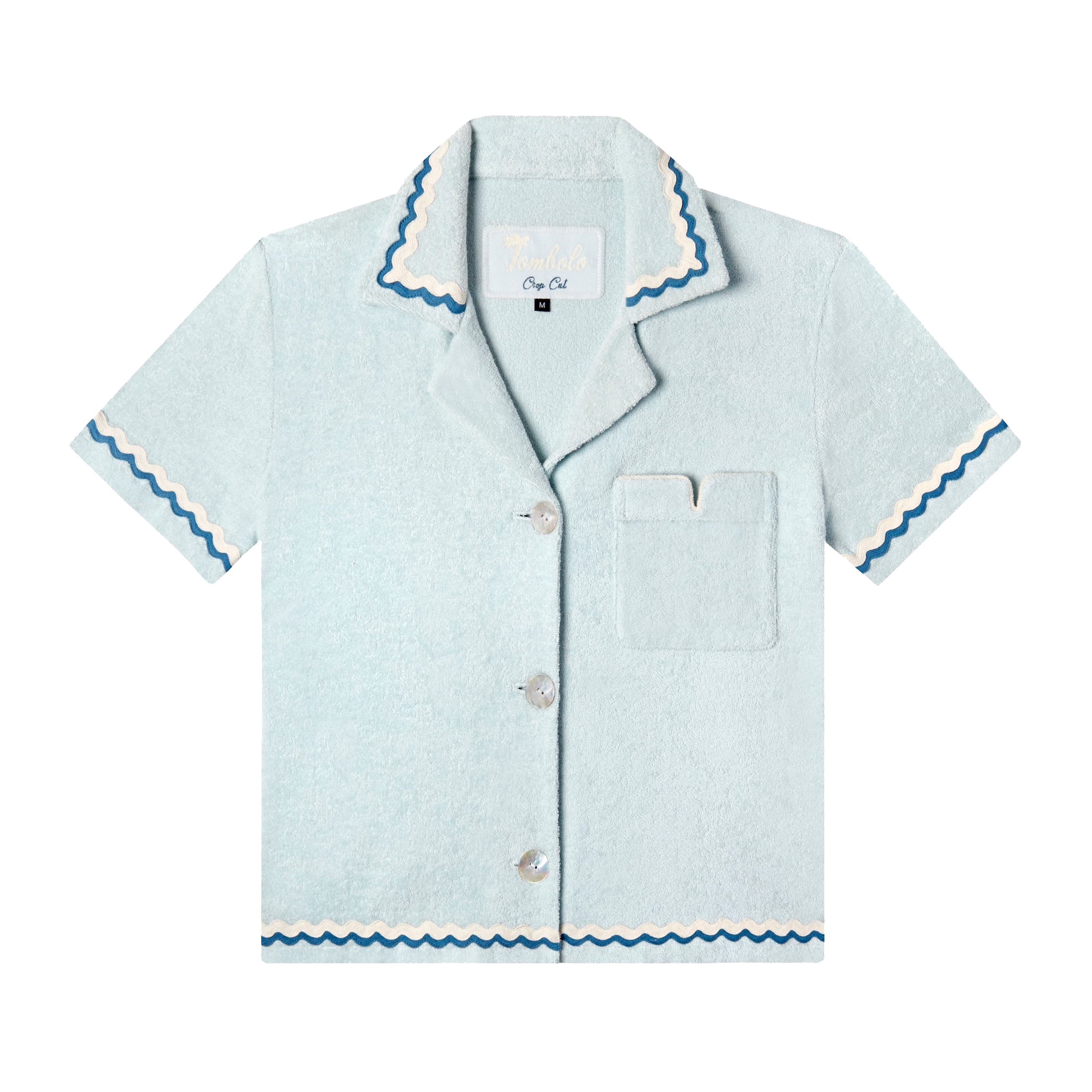 Front-facing product image for the 'Rick Rack' Cabana ~ Crop Cut (Sky Blue) made of Organic Cotton Terry Cloth and featuring oversized agoya shell buttons, signature Tombolo v-slit pocket on chest, overlapping rick rack embroidery on collar, cuffs, and bottom sweep, and a custom woven Tombolo label.