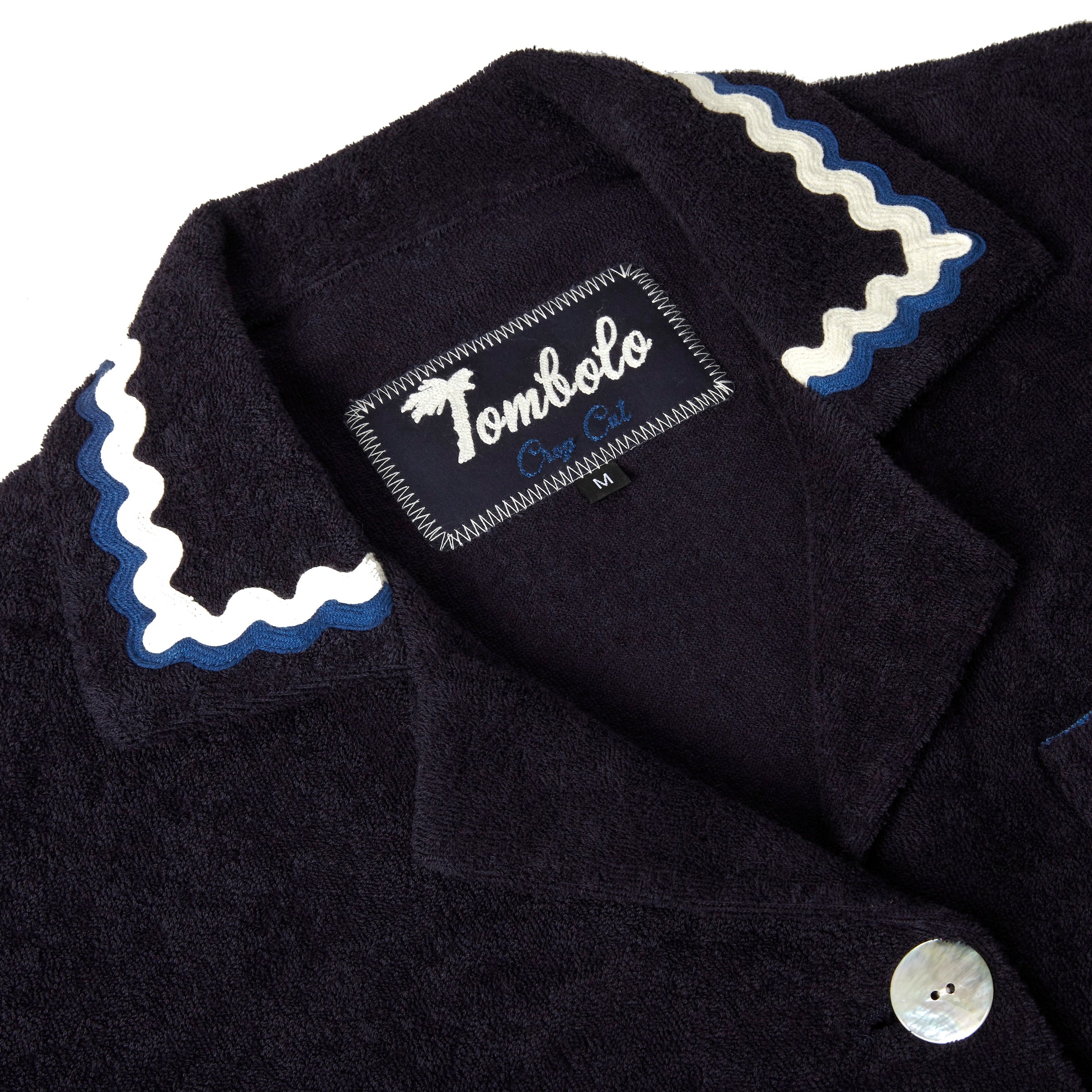 Close-up product image of the 'Rick Rack' Cabana ~ Crop Cut's (Midnight Blue) custom woven Tombolo label and oversized agoya shell buttons.