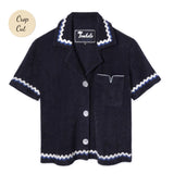 Front-facing product image of the 'Rick Rack' Cabana ~ Crop Cut (Midnight Blue) made of Organic Cotton Terry Cloth and featuring and featuring oversized agoya shell buttons, signature Tombolo v-slit pocket on chest, overlapping rick rack embroidery on collar, cuffs, and bottom sweep, and a custom woven Tombolo label.