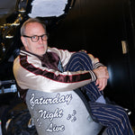 SNL costume designer, Tom Broecker, is seen sitting in the SNL studio, while wearing the 'SNL" Souvenir Jacket and Navy Easy Going Striped pants. 
