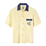 A pale yellow terry cloth short-sleeved shirt with mid-wash denim details, featuring a 'Saturday Night Live' logo on the chest pocket and custom snap buttons.