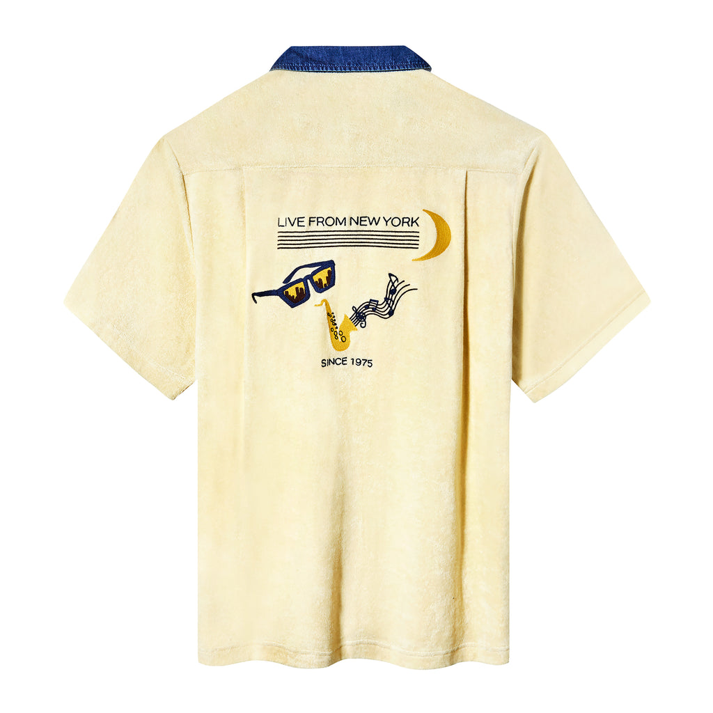 Backside of pale yellow terry cloth cabana shirt, featuring original artwork chain-stitched on the back, paying homage to SNL’s rich history of musical guests and the promise of a crescent moon rising over the greatest city in the world on a Saturday night.