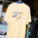 Backside of pale yellow terry cloth cabana shirt, featuring original artwork chain-stitched on the back, paying homage to SNL’s rich history of musical guests and the promise of a crescent moon rising over the greatest city in the world on a Saturday night.