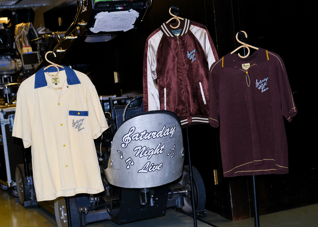 Full 'SNL x Tombolo' collection, hanging on wooden hangers at the SNL studio.