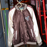 A satin souvenir jacket with 'Saturday Night Live' text and design elements, featuring a mix of maroon, beige, and white colors with red piping.