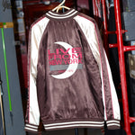 Maroon and cream satin souvenir jacket with striped cuffs and collar. The back features a large embroidered design with a crescent moon and text reading 'Live From New York' and 'Since 1975' in red and teal.