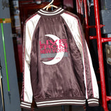 Maroon and cream satin souvenir jacket with striped cuffs and collar. The back features a large embroidered design with a crescent moon and text reading 'Live From New York' and 'Since 1975' in red and teal.