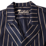 Close-up product image of the Tombolo stitched logo on the inside of the easy-going jacket in navy jacquard stripe, shot on a white background.