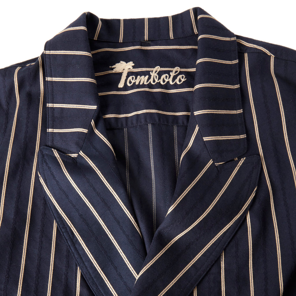 Close-up product image of the Tombolo stitched logo on the inside of the easy-going jacket in navy jacquard stripe, shot on a white background.