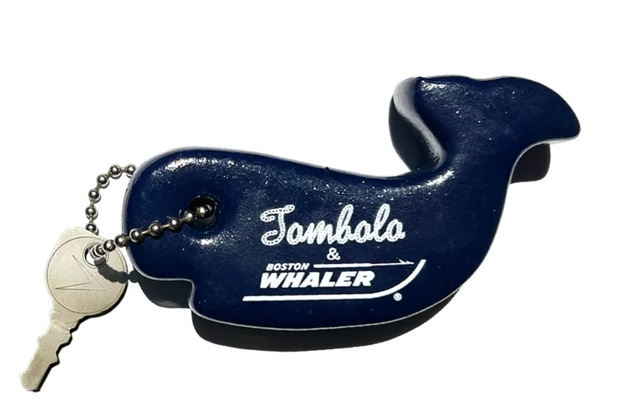Front-facing product image of the 'Boston Whaler' Key Float that features a durable foam with silk-screened 'Tombolo x Boston Whaler' logo lockup, bead chain attachment for keys, that is made in the USA and intended to help keep your keys afloat.