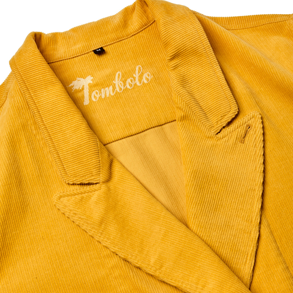 Close-up product image of the yellow corduroy collar, and the interior stitching reading 'Tombolo'. 