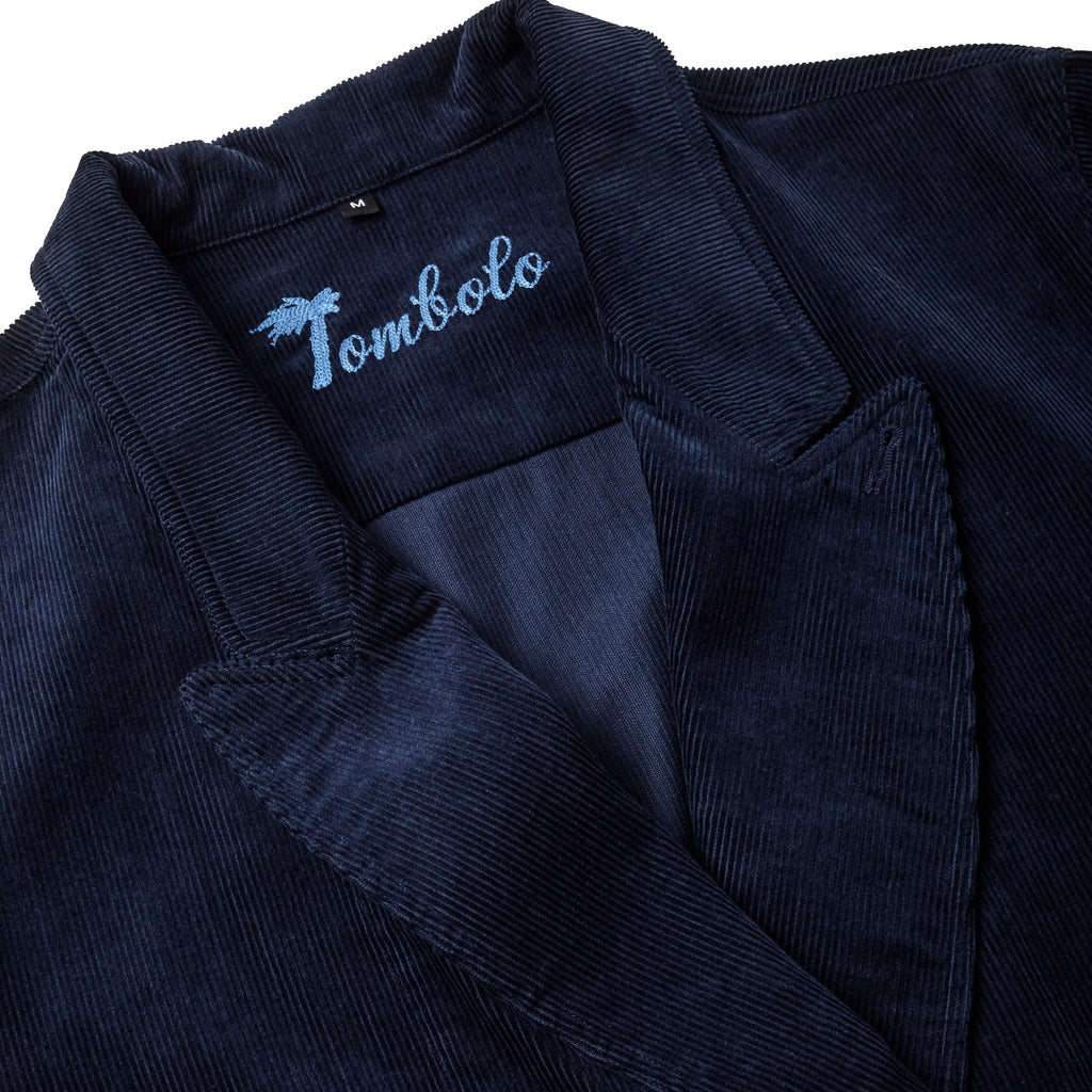 Navy blue corduroy jacket with wide lapels and light blue embroidered 'Tombolo' logo inside the collar.
