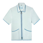 Front-facing product image of the 'Standard Issue' Cabana (Sky Blue) made of 100% Organic Terry Cloth with a two-way, antique-brass ring pull zipper, twin curved patch pockets, chain-stitched Tombolo interior label, and a 1/8" edge binding along collar, zipper, and pockets, all shot on a white background.