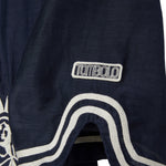 Navy blue shirt with white embroidery and white 'Tombolo' logo patch.