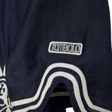 Navy blue shirt with white embroidery and white 'Tombolo' logo patch.